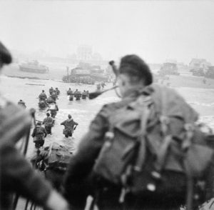 1. Special Service Brigade lander på Sword QUEEN Red. Bill Millin med rygsæk og sækkepibe. Lord Lovat i vandet lige til venstre for Millin.